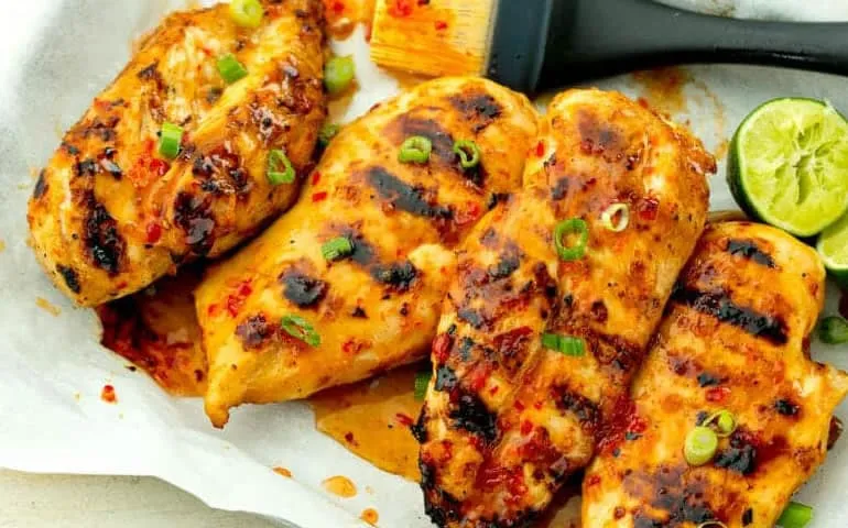 Grilled chicken plated with lime wedges