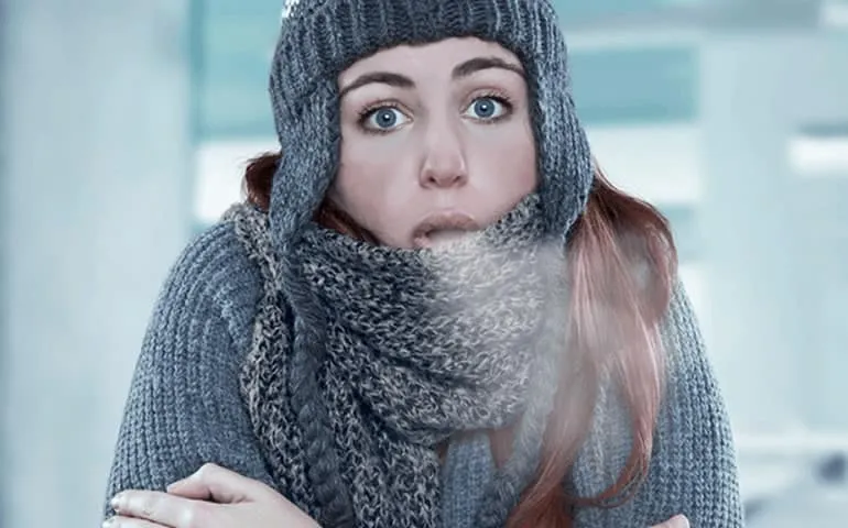 Woman bundled up in a scarf and hat outdoors in winter