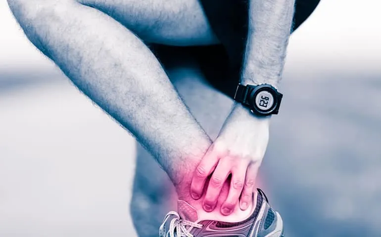 Person holding their ankle with a highlighted area of pain