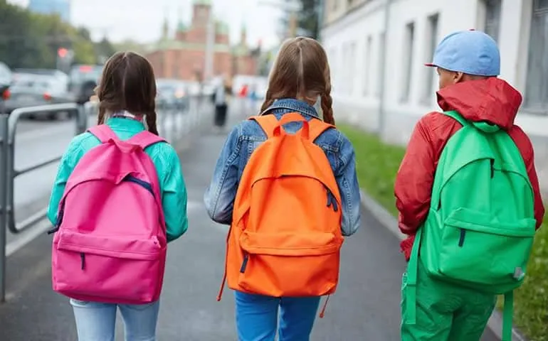 Children walking to school wearing backpacks