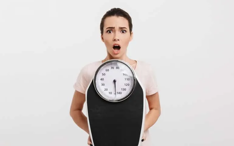 Woman looking shocked while holding a bathroom scale