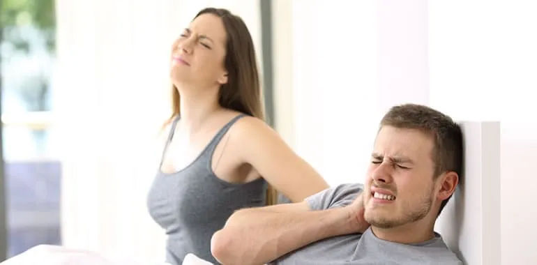 Two people each holding their necks in pain