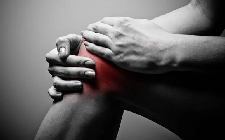 Close-up of hands holding a knee with a highlighted area of pain