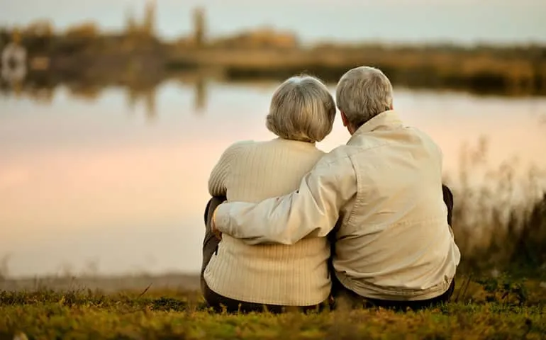 Older couple sitting together outdoors by the water