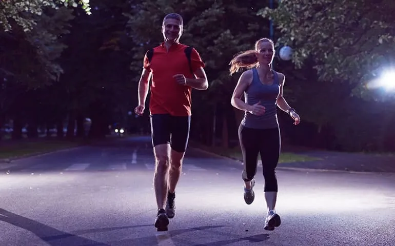 Two runners on a road at night