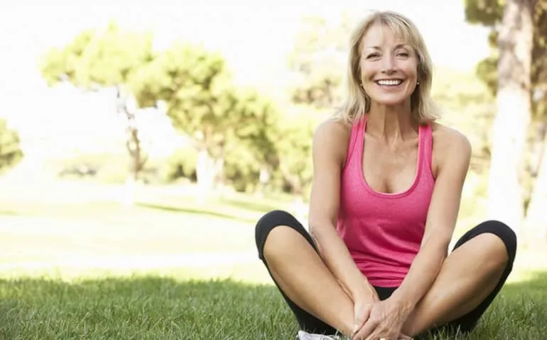 Woman sitting cross-legged and smiling outdoors